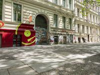 a restaurant in the middle of a narrow city street with graffiti on the wall and the sidewalk outside the building