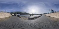 a fisheye view from the bottom of the walkway that is in front of a brick wall and bridge