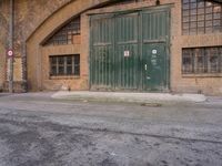 an empty parking lot next to an old building that has a green door that says warehouse square