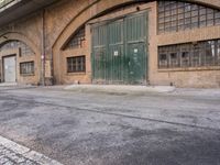 an empty parking lot next to an old building that has a green door that says warehouse square