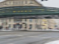 this person is riding a bike underneath an overhead bridge in the city on a snowy day