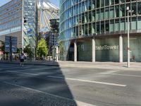 a large building on the corner of an intersection in city with cars on the sidewalk