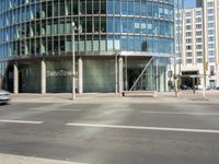 a large building on the corner of an intersection in city with cars on the sidewalk