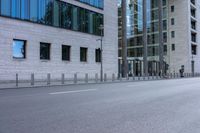 a person with a helmet and suitcase rides a bike down the street near buildings in the background