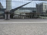 a person sitting on the ground near a large glass building with a black nike logo