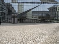 a person sitting on the ground near a large glass building with a black nike logo