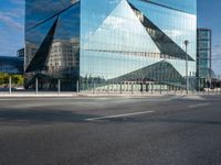 the reflection of mountains is shown in this glass skyscraper that reflects the surrounding buildings along a street