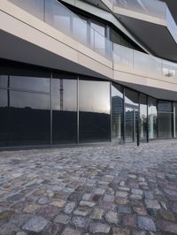 the large building is built from stone with glass walls on it's sides and floor tiles in front of the facade