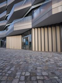 the large building is built from stone with glass walls on it's sides and floor tiles in front of the facade