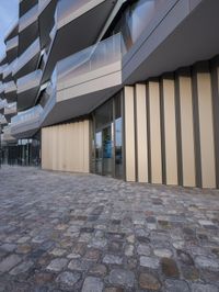 the large building is built from stone with glass walls on it's sides and floor tiles in front of the facade