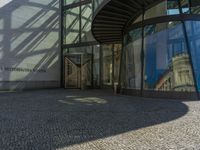 a glass walled entrance to a building on a sunny day with a blue sky reflected in its glass