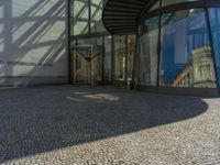 a glass walled entrance to a building on a sunny day with a blue sky reflected in its glass