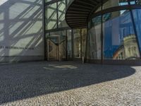 a glass walled entrance to a building on a sunny day with a blue sky reflected in its glass