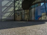 a glass walled entrance to a building on a sunny day with a blue sky reflected in its glass