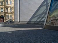 Berlin's Glass Walls and Hard Shadows on Cobblestone Streets