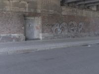 a brick building covered in graffiti next to an empty street way in front of it