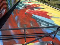 a skateboarder riding the railing on a colorful painted ramp on a sunny day