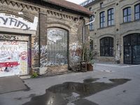 an old brick building with lots of graffiti on the side of it and puddles of water