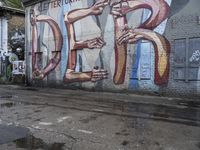 an image of graffiti on a building next to a puddle of water in the sidewalk