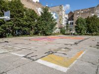 an empty basketball court has graffiti painted on it in the middle of a city sidewalk