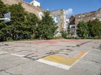 an empty basketball court has graffiti painted on it in the middle of a city sidewalk