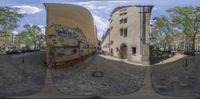 a street with graffiti covered buildings and trees around it and one person riding his skateboard