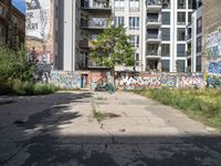 a street has a building with graffiti on it, and green grass in the foreground