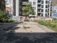 a street has a building with graffiti on it, and green grass in the foreground