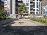 a street has a building with graffiti on it, and green grass in the foreground