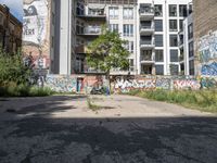 a street has a building with graffiti on it, and green grass in the foreground