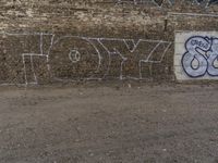 graffiti writing on a brick wall with a sky background in front of the walls and ground is dirt