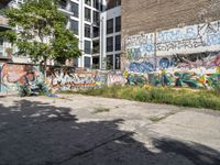 a large building with graffiti on the wall next to some other building with trees and plants