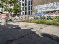 a large building with graffiti on the wall next to some other building with trees and plants