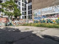 a large building with graffiti on the wall next to some other building with trees and plants