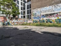 a large building with graffiti on the wall next to some other building with trees and plants