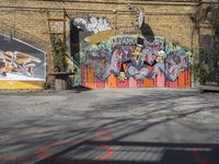 a brick wall with some graffiti painted on it, with a building in the background