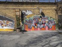 a brick wall with some graffiti painted on it, with a building in the background