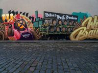 a wall painting on a brick surface with a lot of beer barrels and people near by