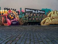 a wall painting on a brick surface with a lot of beer barrels and people near by