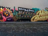 a wall painting on a brick surface with a lot of beer barrels and people near by