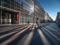 the sunlight reflects from several windows in a large building onto the street from outside the building