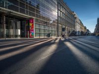 the sunlight reflects from several windows in a large building onto the street from outside the building