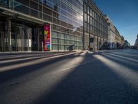 the sunlight reflects from several windows in a large building onto the street from outside the building