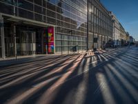 the sunlight reflects from several windows in a large building onto the street from outside the building