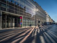 the sunlight reflects from several windows in a large building onto the street from outside the building