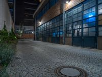 some dark blue windows in an industrial building with no one on the street to the right