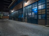 some dark blue windows in an industrial building with no one on the street to the right