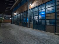 some dark blue windows in an industrial building with no one on the street to the right