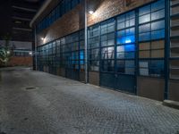 some dark blue windows in an industrial building with no one on the street to the right