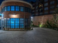 some dark blue windows in an industrial building with no one on the street to the right